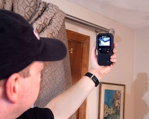 Man Holding Leak detection device locating a leak in building via thermal imaging 